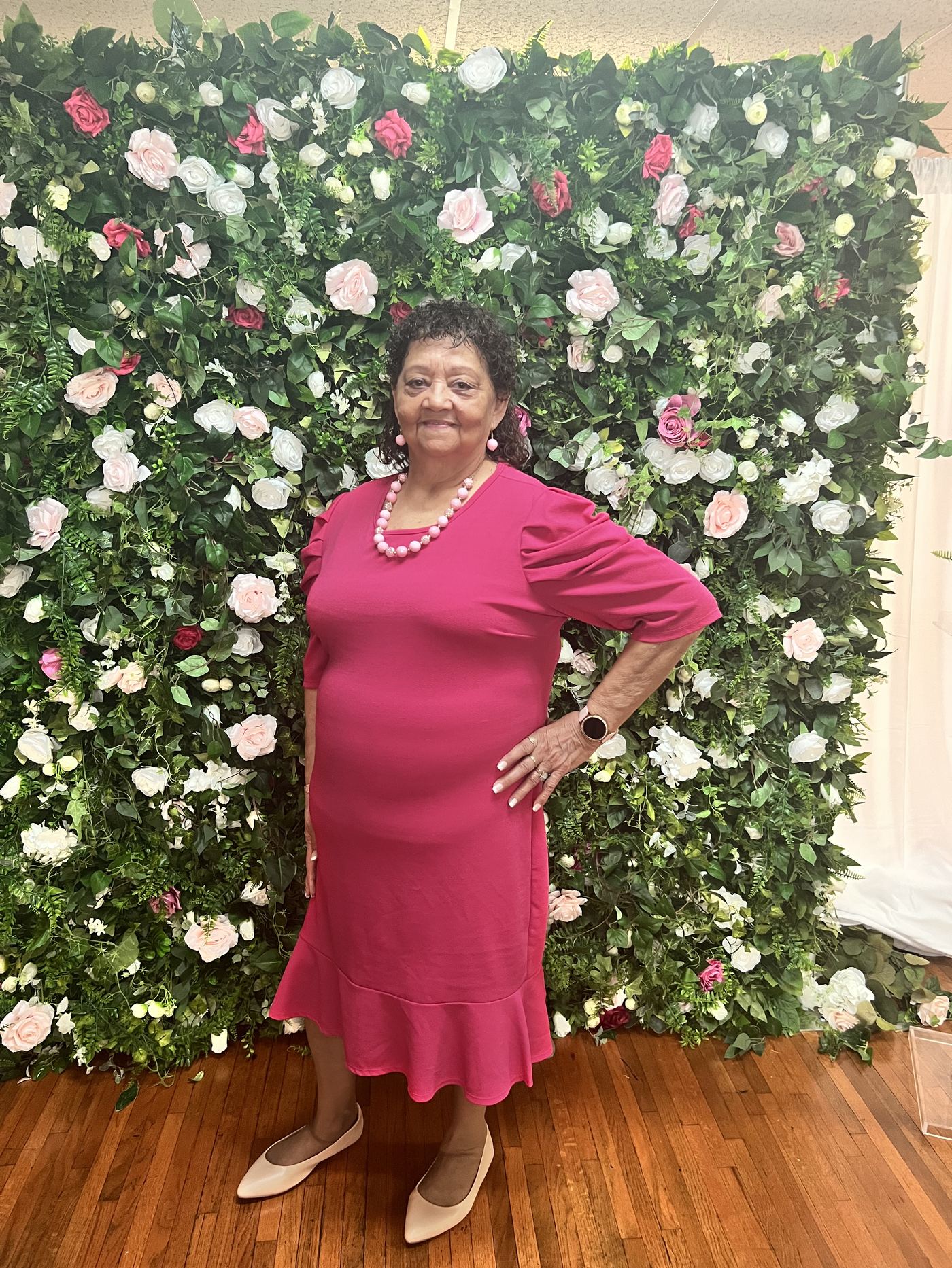 Guest posing at the floral wall in a pink dress