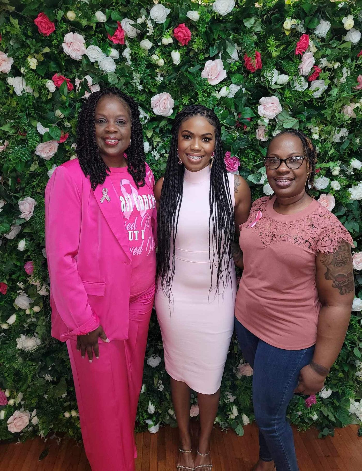 Three guests posing at the floral wall