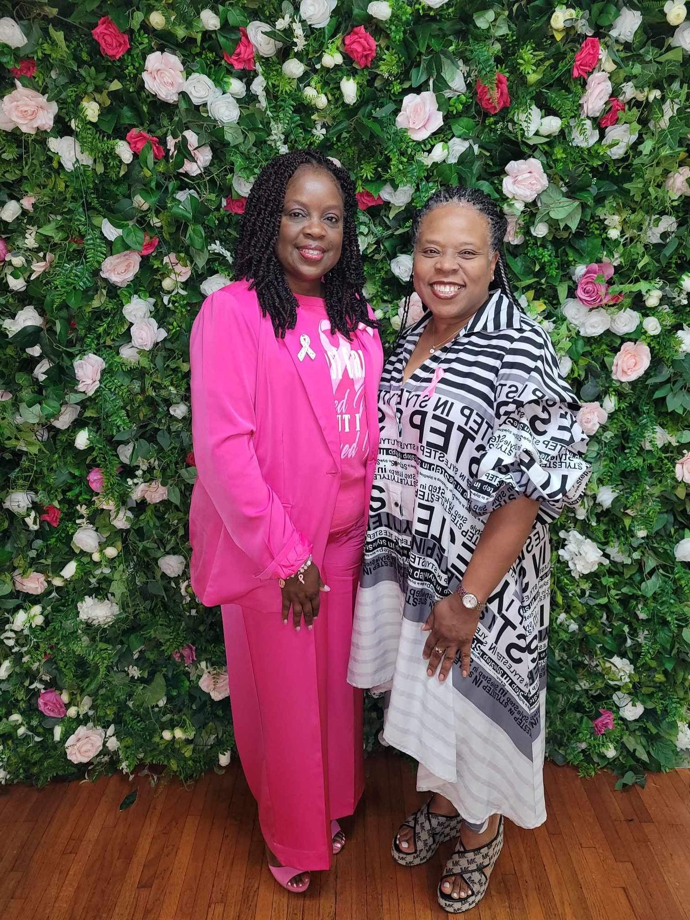 Two survivors smiling at the floral wall